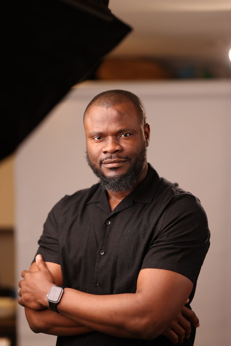 Elvis C. Umez standing with arms folded in a photography studio